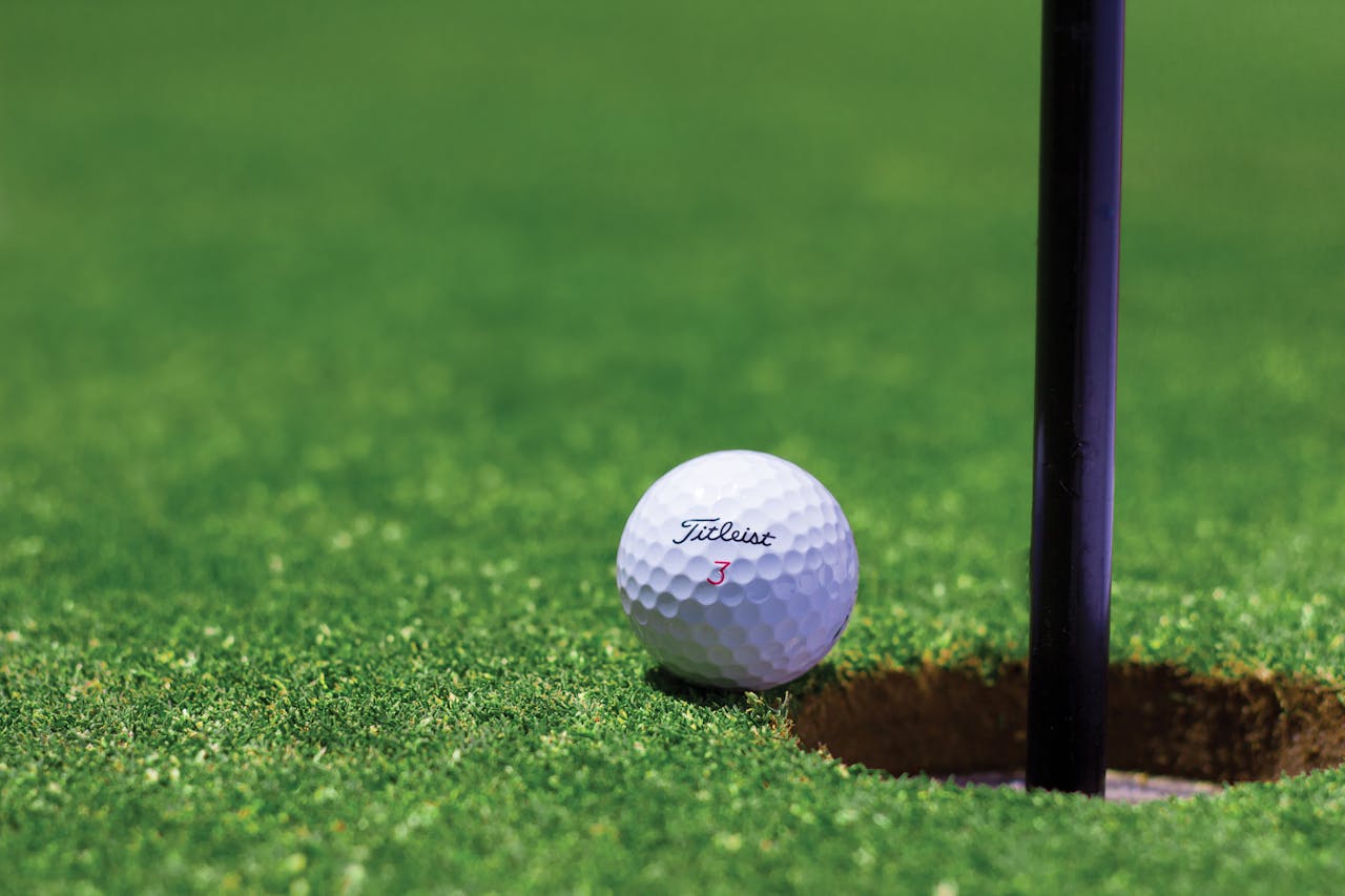 Services-01 Close-up of a golf ball near a hole on a vibrant golf green, capturing the moment of near success.